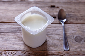 Natural yogurt in a plastic container on a rustic table