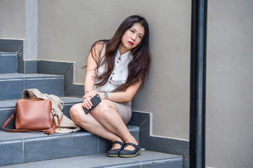 desperate Asian Korean businesswoman crying alone sitting on street staircase suffering stress and...