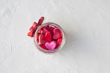 Valentine's day concept. jar with small hearts red and pink on a light background.