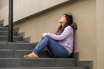 depressed Asian Chinese student woman or bullied teenager sitting outdoors on street staircase overwhelmed and anxious feeling desperate suffering depression