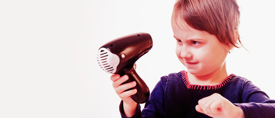 Humorous portrait of cute little girl brushing her hair with dryer. Hair, beauty, care concept.