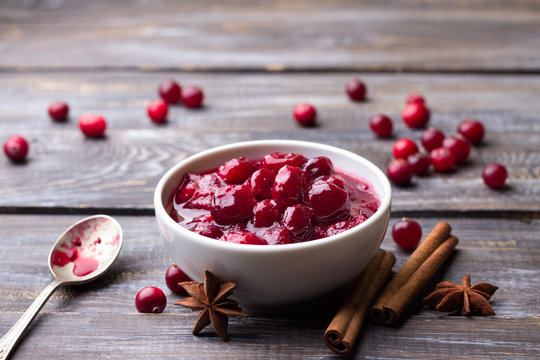 Homemade spicy cranberry sauce with fresh cranberries, cinnamon and star anise on a wooden background