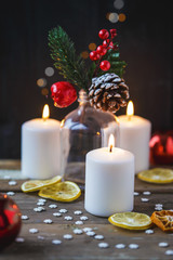 Christmas decorations, burning candles, candy ,citrus, spruce on a wooden background. New Year's concept. Postcard
