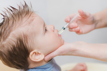 mom gives the baby fish oil through a syringe