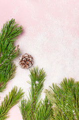Christmas background, green pine branches, cones decorated with snow on snowy pink background. Creative composition with border and copy space design top view. New Year's, holiday, decoration