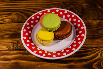 Plate with french macaroons on rustic wooden table. Top view