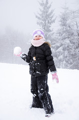 Fototapeta na wymiar child with snowball in winter forest