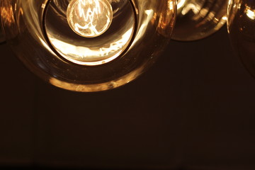 Glass ceiling and  Edison light  bulb   on dark background with space for text. Close-up.