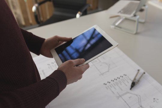 Midsection of architect using digital tablet in office