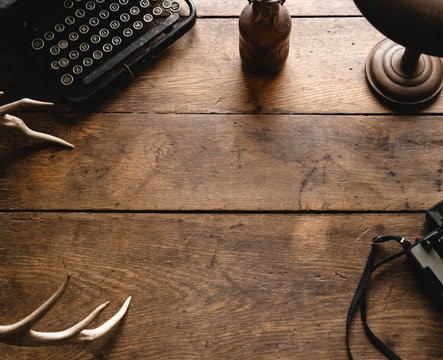 Vintage Hipster Wooden Table Desk Background Texture Great for Display and Mockup with Old Camera, Black Typewriter, Bronze Lamp, White Deer Antlers and Old Retro Bottle 