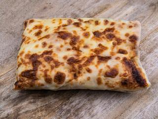 French Tacos with Gratin Cheese on top close up on Wood Board 1