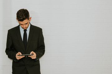 business man in white wall consulting the device or tablet