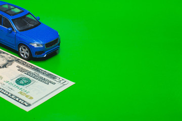 blue toy car and dollars on a green background