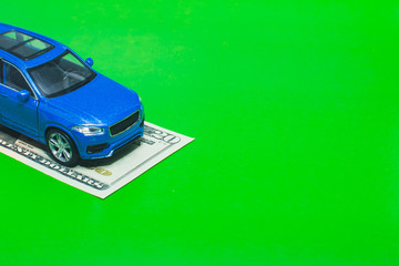 Blue toy car on dollars. Green background