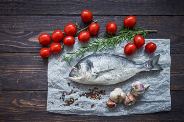 Raw dorado fish with vegetables on rustic background. Sea bream or dorada fish. Top view, copy space
