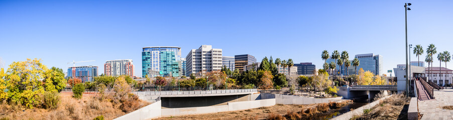 Panoramic view of San Jose's downtown skyline as seen from the shoreline of Guadalupe river on a sunny fall day; Silicon Valley, California - obrazy, fototapety, plakaty