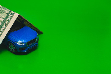 blue toy car under dollars on a green background