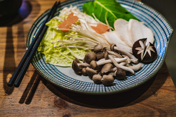 Hot Pot set on a wooden taple in a Korean restaurant. Fresh vegetables