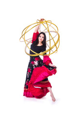 A young,smiling girl in a long skirt dancing with a Hoop.