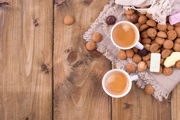 Two cups of aromatic coffee for a good Christmas. Dutch holiday Sinterklaas background, gifts, pepernoten, traditional sweets strooigoed. Flat lay and copy space. Vintage wooden background.