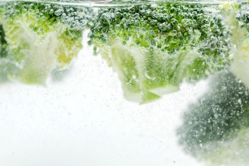 Pieces of appetizing broccoli in clear water.
