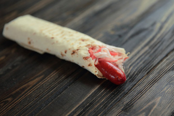 pork sausage and lettuce wrapped in pita bread on wooden backgro