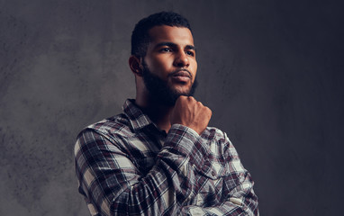 Portrait of a pensive African-American guy with a beard wearing a checkered shirt