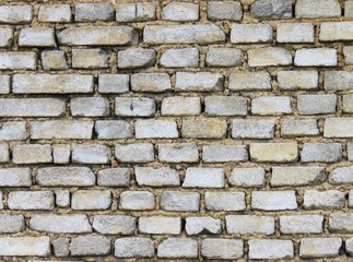 Old brick gray wall, the wall of a house without plaster. Many bricks connected by mortar. Old method of masonry. Construction, background, wallpaper.