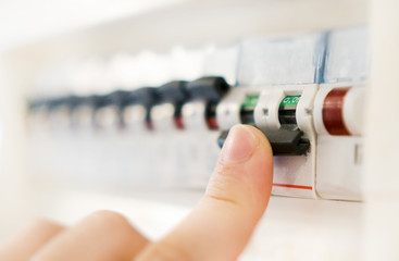 Male hand switching off fuse board. - obrazy, fototapety, plakaty