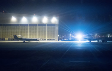 Passenger planes near hangar at night airport. - obrazy, fototapety, plakaty