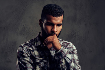 Portrait of a pensive African-American guy with a beard wearing a checkered shirt