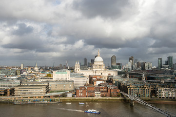 Fototapeta na wymiar Scenic overcast view of the city skyline with a patch of sun lighting St Paul’s Cathedral above the River Thames in London, England