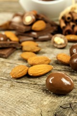 Almonds in chocolate glaze on a old wooden table. Unhealthy food. Risk of obesity and diabetes. Sweet nuts. Almond chocolate dragees