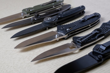 Folding knives on a wooden background.