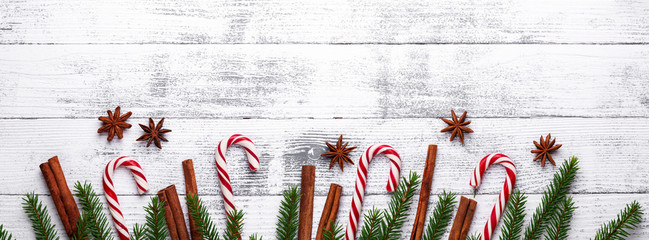 Christmas background. Fir branches, candy cane and gifts on a light wooden background. Cranberries,...