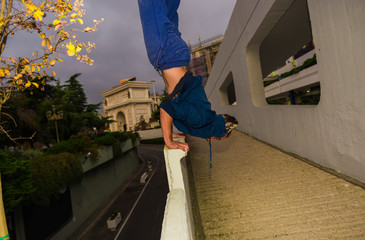 Young parkour man perform handstand at urban place