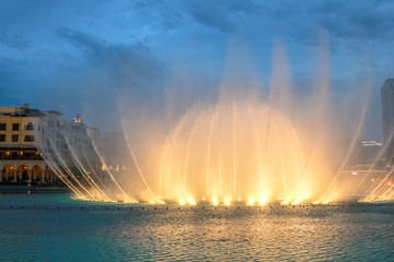 Obraz premium Nocny widok pokazu świateł w tańczącej fontannie w Dubaju. Dubajska fontanna, największa na świecie fontanna z choreografią na obszarze jeziora Burj Khalifa, gra w rytm wybranej muzyki.