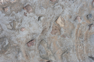 Gray neutral background with rare stones, pebbles, poured cement, concrete. Homemade path in the garden on a cloudy day.