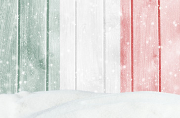 Christmas winter background with wooden wall, falling snow, snowdrift and Italian flag