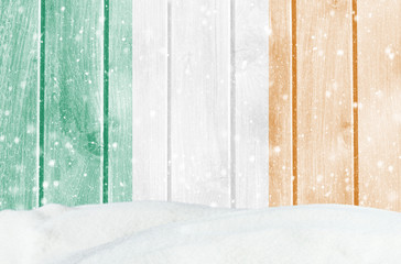 Christmas winter background with wooden wall, falling snow, snowdrift and Irish flag