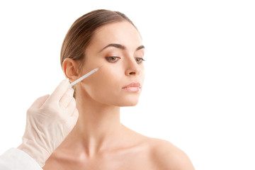 Woman at plastic surgery. Portrait of an attractive young woman receiving botox treatment. Isolated...