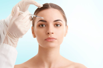 Woman at plastic surgery. Portrait of an attractive young woman receiving botox treatment. Isolated...