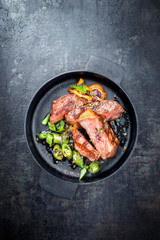 Modern Style classic dry aged sliced roast beef with fried onion rings and chili served as top view in a minimalistic design cast-iron skillet