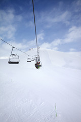 Chair-lift, snowy ski slope and cloudy sky with falling snow