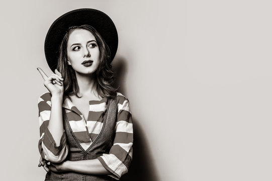 Portrait of young surprised white european woman in hat and striped shirt with jeans dress . Image in black and white color style