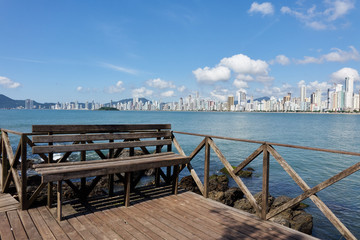 Steg und Ruhebank mit Blick auf die Skyline der Strand-Stadt Balneario Camboriu