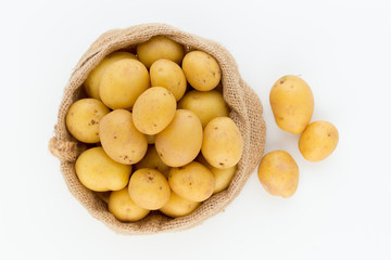 Sack of fresh raw potatoes on wooden background, top view