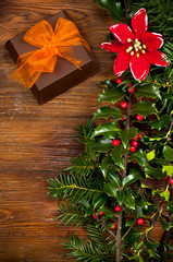 one ornamentally wrapped gift, holly and flower of star of Bethlehem on wooden table