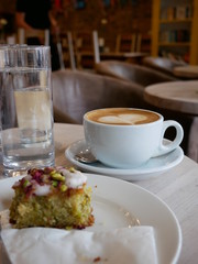 flat white with heart latte art with slice of pistachio cake