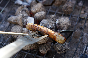 Open fire in the grill to grill a sausage with a charcoal barbecue in the garden